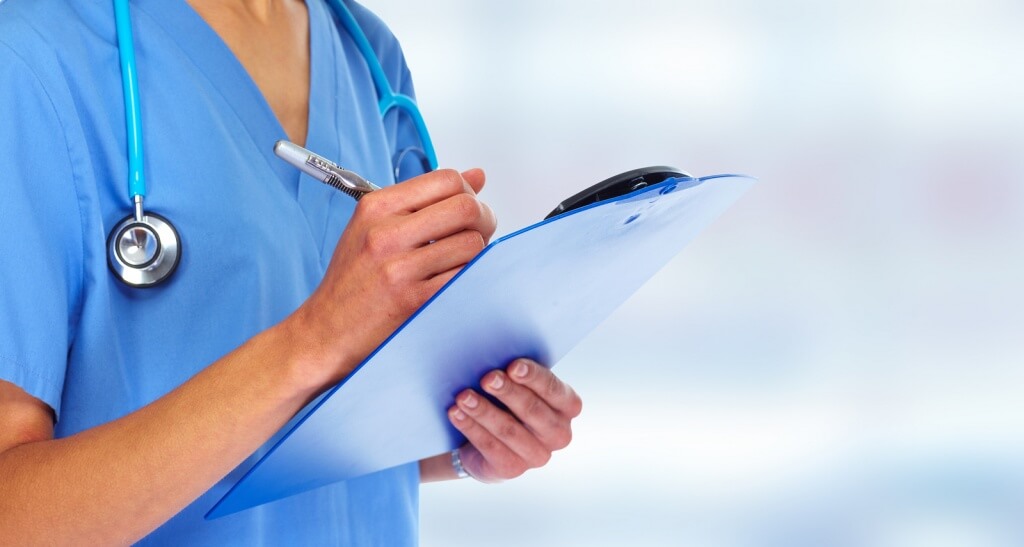Doctor hands writing on a clipboard.
