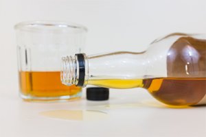 close up of alcohol bottle spilling with glass