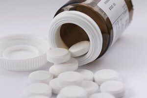 Pills and medicine container lying on white background