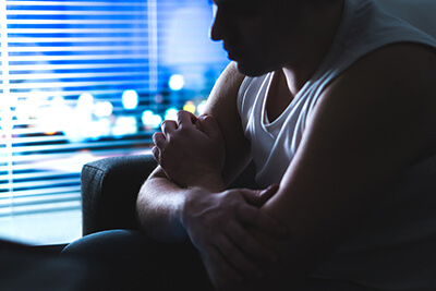 Thoughtful, pensive and contemplating man thinking in dark home at night by the window.