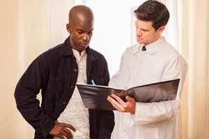 Male black men looking over notes with male white medical physician