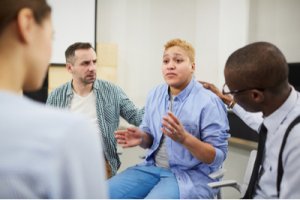 Portrait of mixed raced woman sharing troubles emotionally during group therapy session