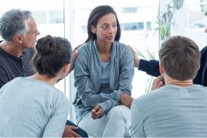 Concerned people comforting another in rehab group at a therapy session
