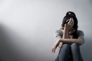 person sitting on the floor against the wall with hand on head